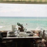brown wooden table and chairs near sea during daytime